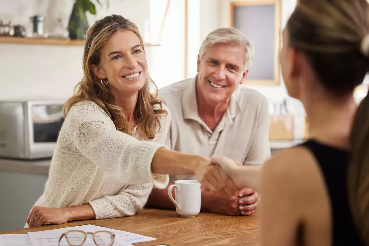 Middle aged couple shaking hands with agent